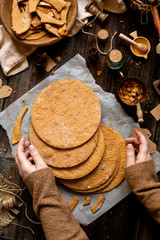 Overhead shot of homemade baked layers of Russian traditional honey cake on baking paper on wooden rustic table