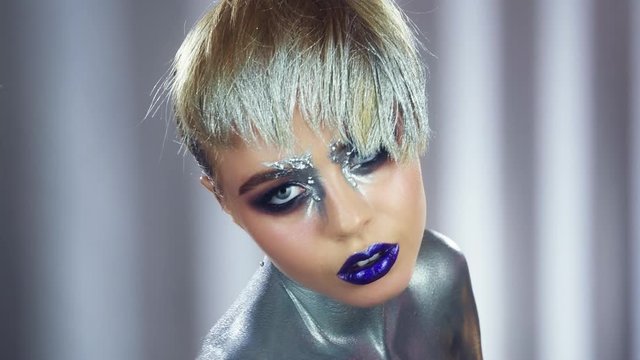 High fashion model. Fashion model woman with trendy metallic make-up posing in studio. Glitter vivid makeup. Fashion makeup