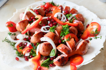 Fried sausages with vegetables on a thin flat cake in a plate. Grilled sausages with vegetables.