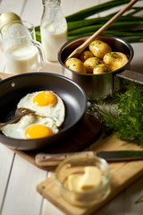 Fried egg with young potatoes with dill and milk on  wooden table