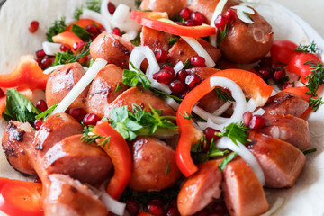 Fried sausages with vegetables on a thin flat cake in a plate. Grilled sausages with vegetables.