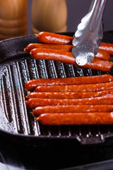 young woman in a gray apron fries sausages