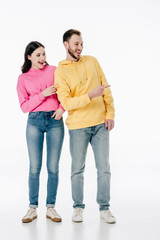 young smiling man and woman in hoodies and blue jeans pointing with fingers on white background
