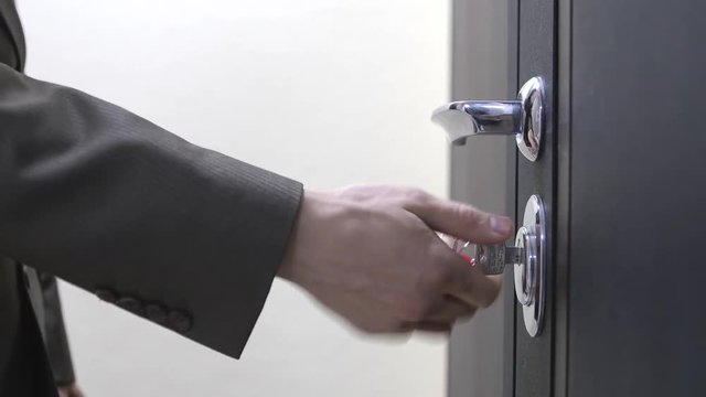 A businessman unlocks a house's door with key and enters. 3840x2160