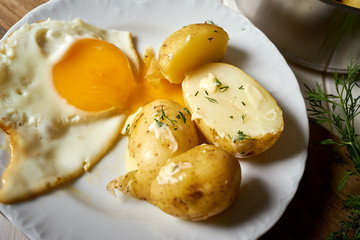 close up on fried eggs with young potatoes with butter and dill
