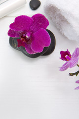 Spa or wellness setting with pink orchids ,towel and black stones.