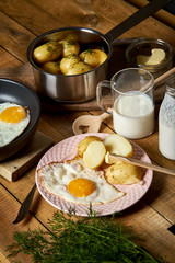 Fried egg with young potatoes with dill and milk on  wooden table