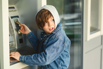 Problems pre teen boy in hood, take money in cash dispenser for alien card. Boy takes cash at ATM...