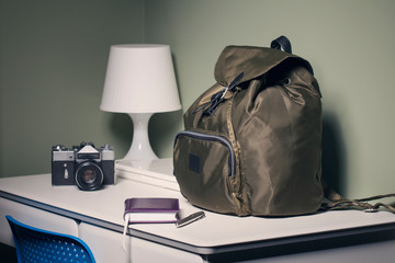 backpack, camera, notebook, notebook and pen on the desk