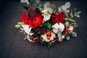Fototapeta na wymiar winter bouquet with red roses, cotton, eucalyptus. bouquet with red ribbon. red ranunculus