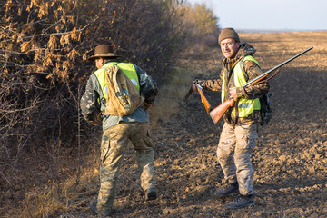 Hunters with a german drathaar and spaniel, pigeon hunting with dogs in reflective vests	