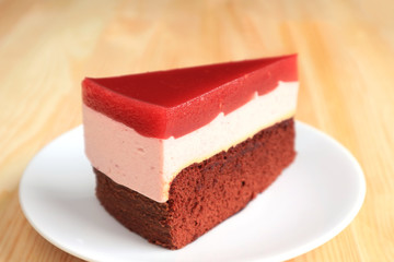 Slice of Raspberry Mousse with Chocolate Layer Cake Served on Wooden Table with Copy Space