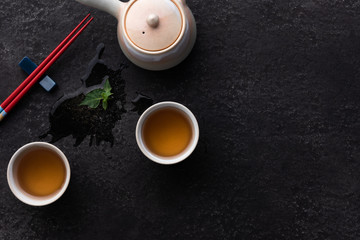 Obraz na płótnie Canvas Top view mockup a cup of tea and tea leaf on the black desk