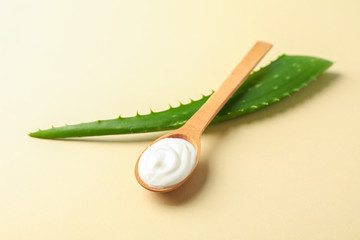 Aloe vera leaf and spoon with cream on color table, space for text and closeup. Natural treatment