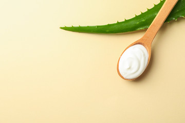 Aloe vera leaf and spoon with cream on color table, space for text and closeup. Natural treatment
