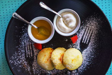 Healthy breakfast cottage cheesecakes Russian sirniki with honey and sour cream for breakfast on blue background. Flat lay, top view, close-up. Selective focus.