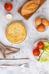 .Tortilla, Spanish omelette made with eggs and potatoes. Traditional Spanish tapas or snack served in white plate with cutlery and napkin. on cement table.