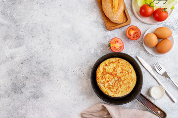 Tortilla Spanish omelette made with eggs and potatoes  on  frying pan served with traditional...