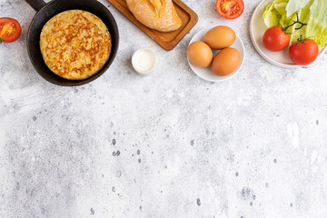 Tortilla Spanish omelette made with eggs and potatoes  on  frying pan served with traditional salad, mayonnaise  and bread. Spanish cuisine background with copyspace.