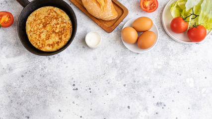 Tortilla Spanish omelette made with eggs and potatoes  on  frying pan served with traditional salad, mayonnaise  and bread. Spanish cuisine background with copyspace.