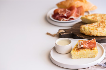  Tortilla,  Spanish omelette made with eggs and potatoes. Traditional Spanish tapa served with mayonnaise   jamon, Iberian ham on white background.