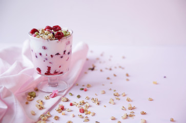 yogurt parfait with fresh raspberry berries on a light pink background. Healthy food. With copy space for text.