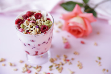 Fototapeta na wymiar yogurt parfait with fresh raspberry berries and rose on a light pink background. Healthy food. With copy space for text.