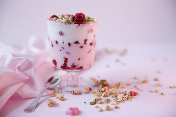 yogurt parfait with fresh raspberry berries on a light pink background. Healthy food. With copy space for text.