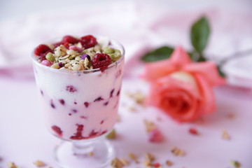 yogurt parfait with fresh raspberry berries and rose on a light pink background. Healthy food. With copy space for text.