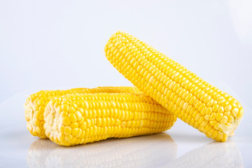 fresh raw sweet corn on the cob kernels over white background