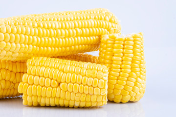 fresh raw sweet corn on the cob kernels over white background