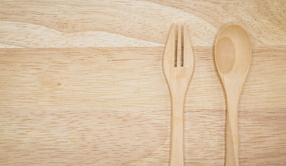 One pair of spoons and forks made of wood, placed on large wooden plates.