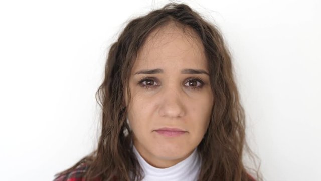 Upset young brunette woman portrait on white background. Sad woman with negative emotion. slow motion. 3840x2160