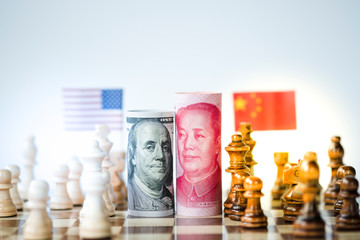 US dollar and Yuan banknote with chess for tariff trade war between United States and China which both countries battle by increase tax barrier of import and export product. Government and business.