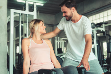 Fototapeta premium Beautiful Woman is Exercised Training With Bodybuilder Machine in Fitness Club., Attractive of Sporty Girl Doing Working Out With Her Trainer in Gym, Healthy and Sport Exercising Lifestyle Concept.