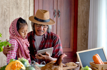 Old man grandfather with hat explain about his menu for cooking to his grandchild by using tablet in the kitchen