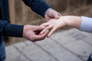 Fototapeta na wymiar 2 anziani si scambiano la fede come promessa di matrimonio