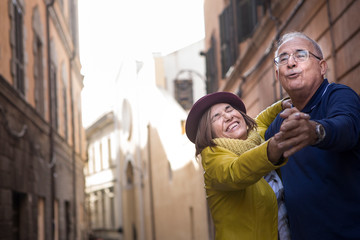 coppia di anziani balla felice in mezzo a una strada - obrazy, fototapety, plakaty
