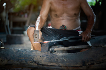 Blacksmith manually forging the molten metal on the anvil