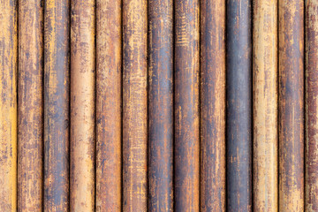 Rusty grunge pipes horizontal background. Orange corrosion rust on steel metal factory industrial pattern. Rough texture brown parallel stack close up