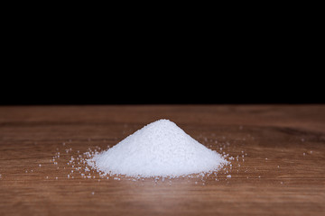 Coarse granules of natural rock or sea salt on a rustic old wooden table.