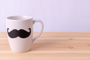Fototapeta na wymiar Happy fathers day concept. Coffee cup with black paper mustache on wooden background. Love Dad my hero.