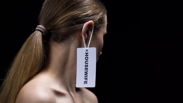 Male hand putting housewife label on female ear, indicating place of women