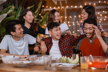 fun young people laughing while having garden party at home and having some dinner