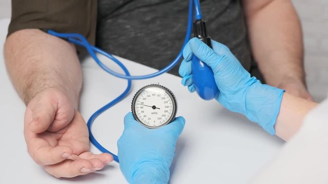 Male patient on reception at the cardiologist. The process of measuring pressure using a mechanical tonometer.