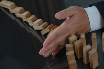 Businessman hand stopping the domino wooden effect concept for business. Risk management concept.