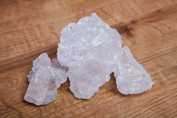 Coarse granules of natural rock or sea salt on a rustic old wooden table.