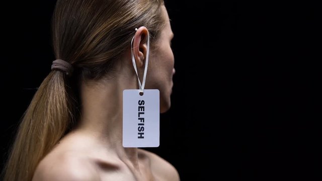 Male hand putting selfish tag on female ear, self sufficiency and independence