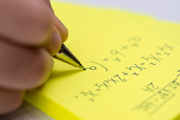 Writing on Yellow Sticky Notes Close Up. Pencil in Children Hand.