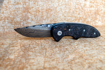Open pocket knife with Damascus steel and Box Elder handle. Defocused to emphasize the object.